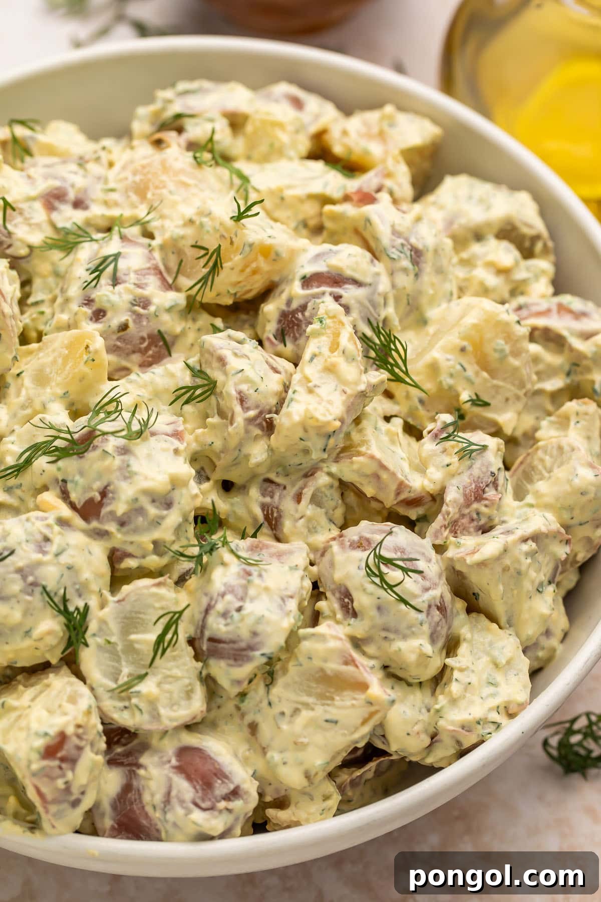 Ruby Red Potato Delight 2 A large white bowl of creamy red potato salad, garnished with fresh herbs, ready to be served at a summer gathering.