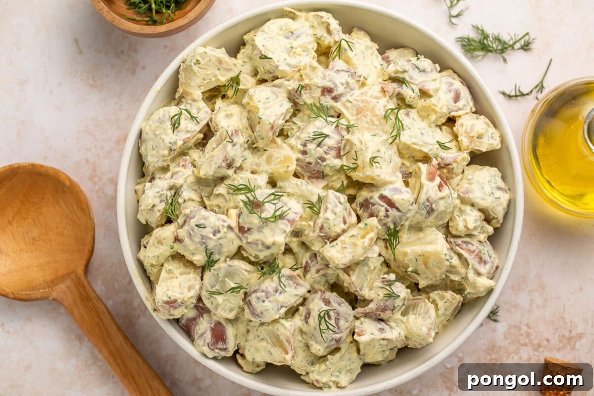 Ruby Red Potato Delight 3 A close-up of the creamy red potato salad in a white bowl, showing tender potatoes and vibrant green herbs.
