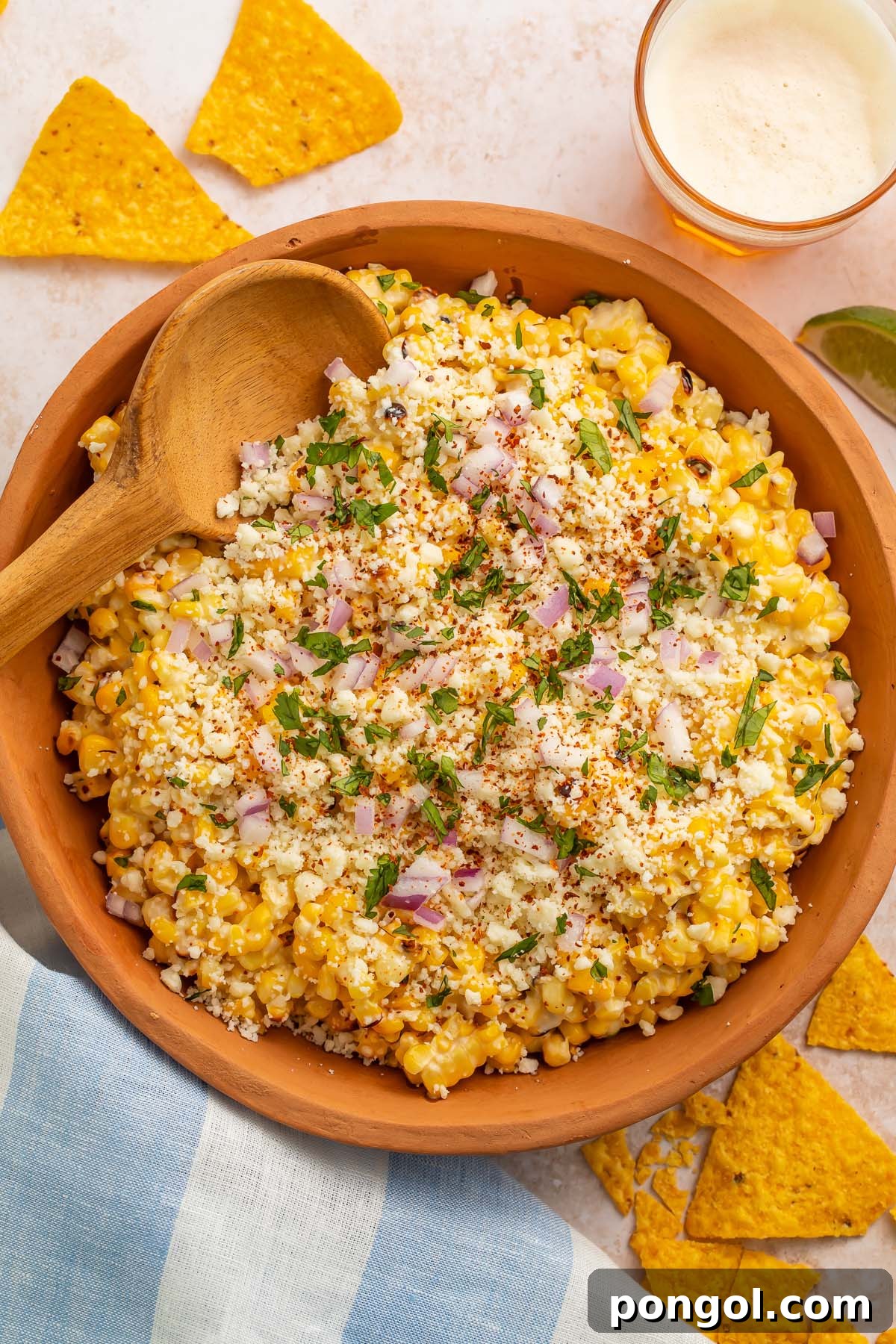 Top-down photo of a large wooden bowl holding a Mexican street corn salad, showcasing vibrant colors and fresh ingredients.