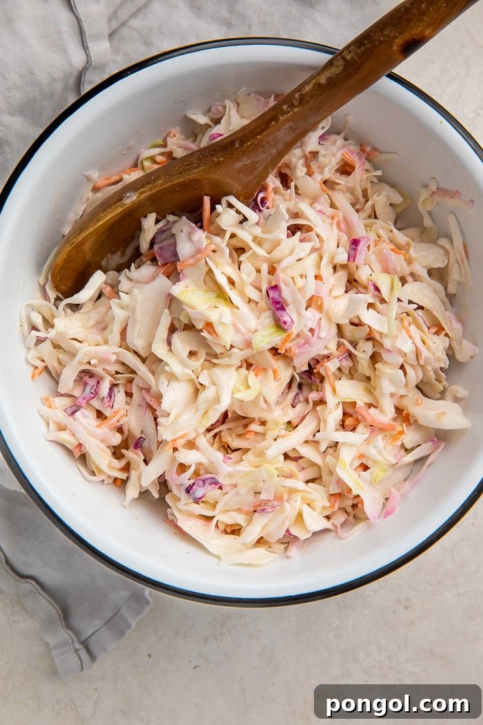 Adding coleslaw mix to the dressing and stirring.