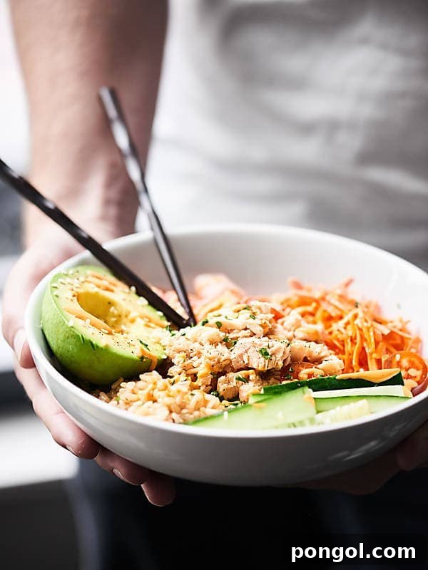 A vibrant Spicy Tuna Roll Bowl, deconstructed sushi with rice, tuna, avocado, and spicy sauce.