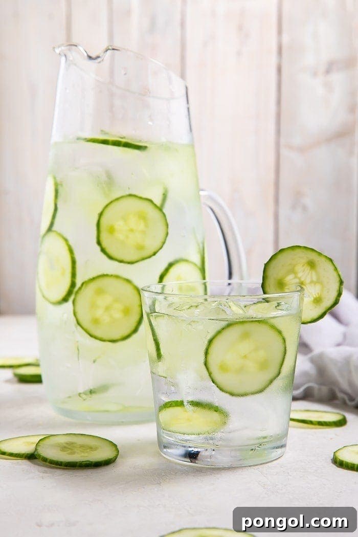 A beautifully arranged pitcher and glass filled with fresh cucumber water, garnished with cucumber slices, perfect for a refreshing summer drink.
