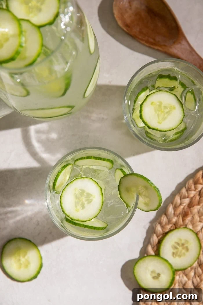 An overhead shot showcasing two elegant glasses and a pitcher brimming with vibrant cucumber water, ready to be served.