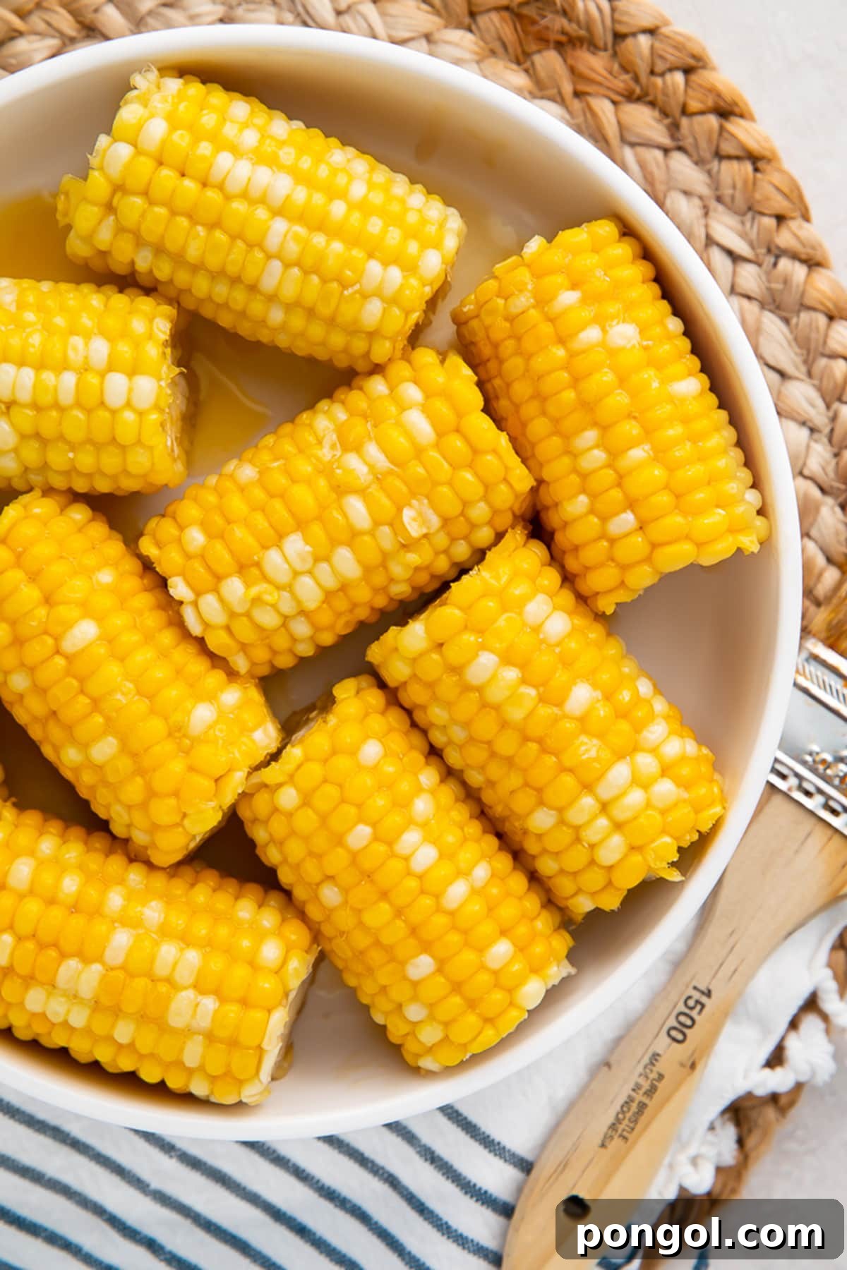 Instant Pot Honey Butter Corn Perfection 2 Instant Pot corn on the cob with a honey butter glaze in a large white bowl on a wicker placemat.
