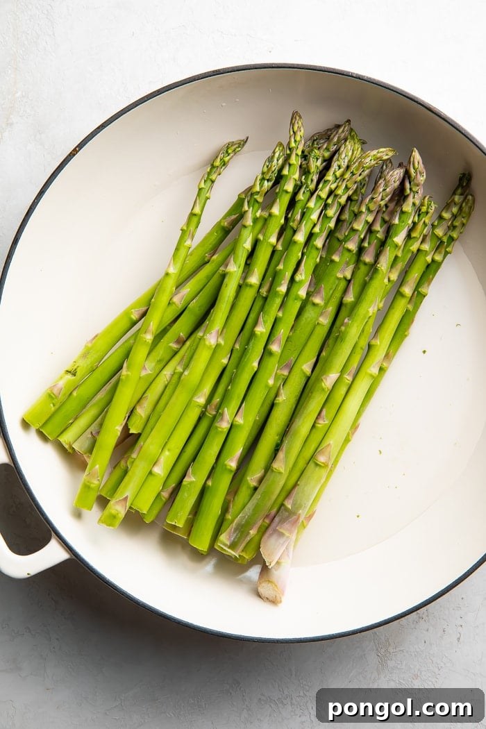 Asparagus stalks being prepared for blanching in a skillet.
