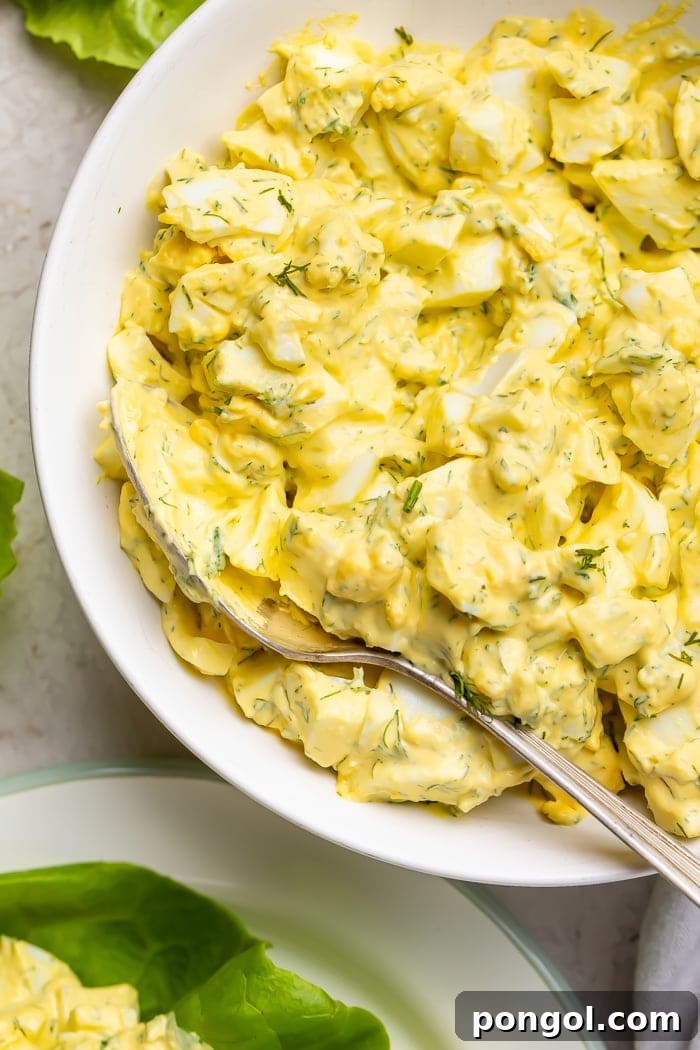 Keto egg salad in a white bowl with a spoon, ready to be served.