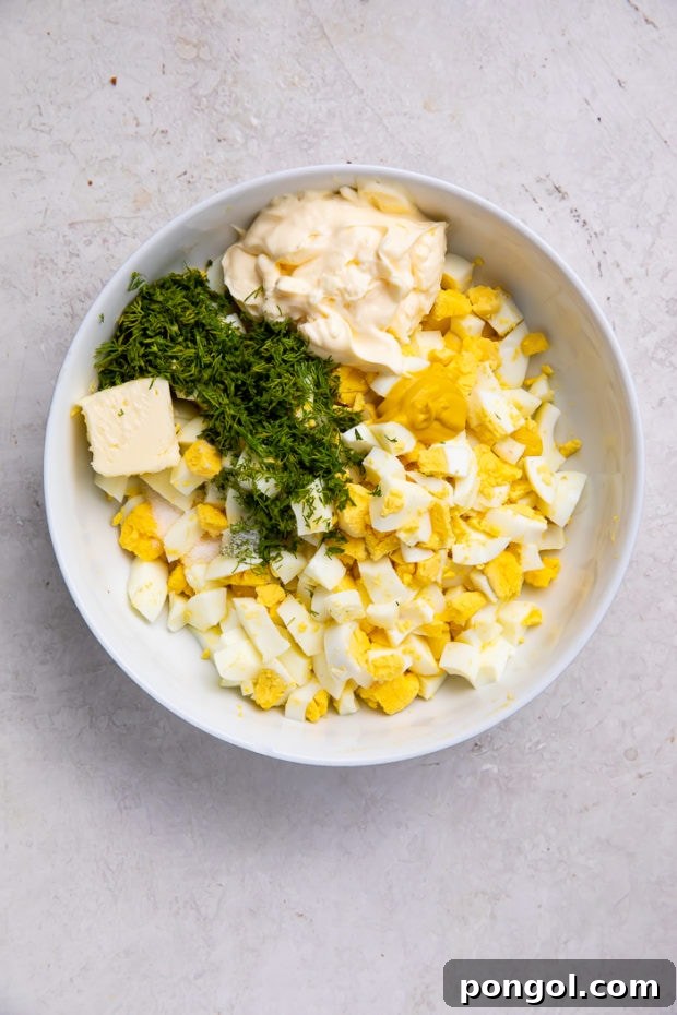 Ingredients for egg salad in a bowl being mixed