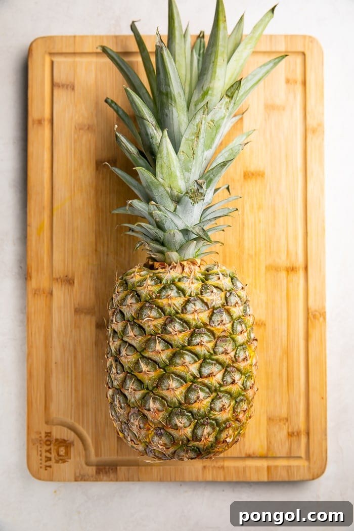 Unlock the Secret to Easy Pineapple Slicing 11 A whole pineapple lying on a cutting board next to a sharp chef's knife