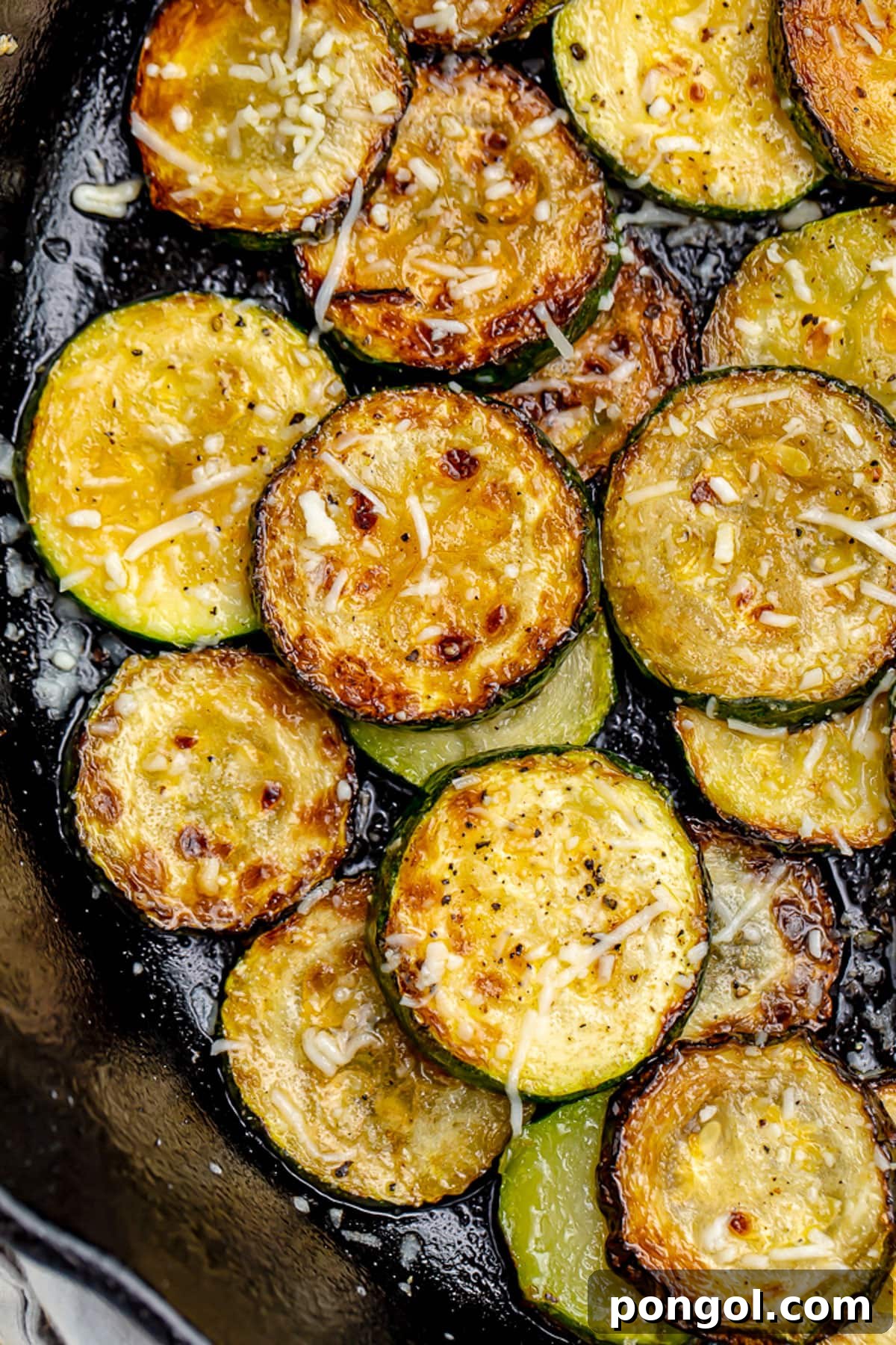 Close-up of perfectly cooked sauteed zucchini discs, garnished with fresh herbs and a sprinkle of cheese.