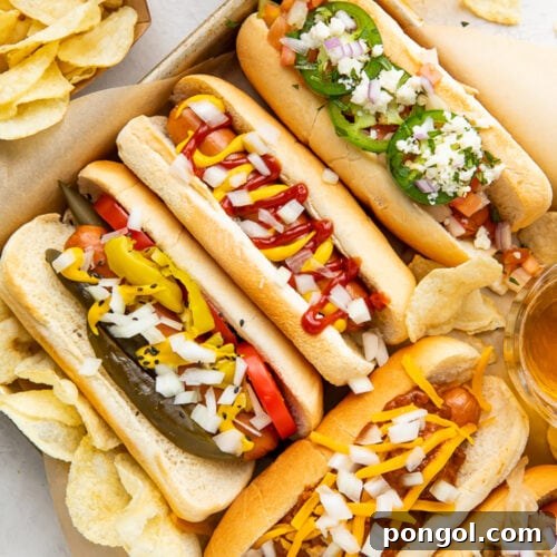 Crispy Air Fryer Hot Dogs 4 Five air fryer hot dogs in hot dog buns with various toppings arranged on a baking sheet.