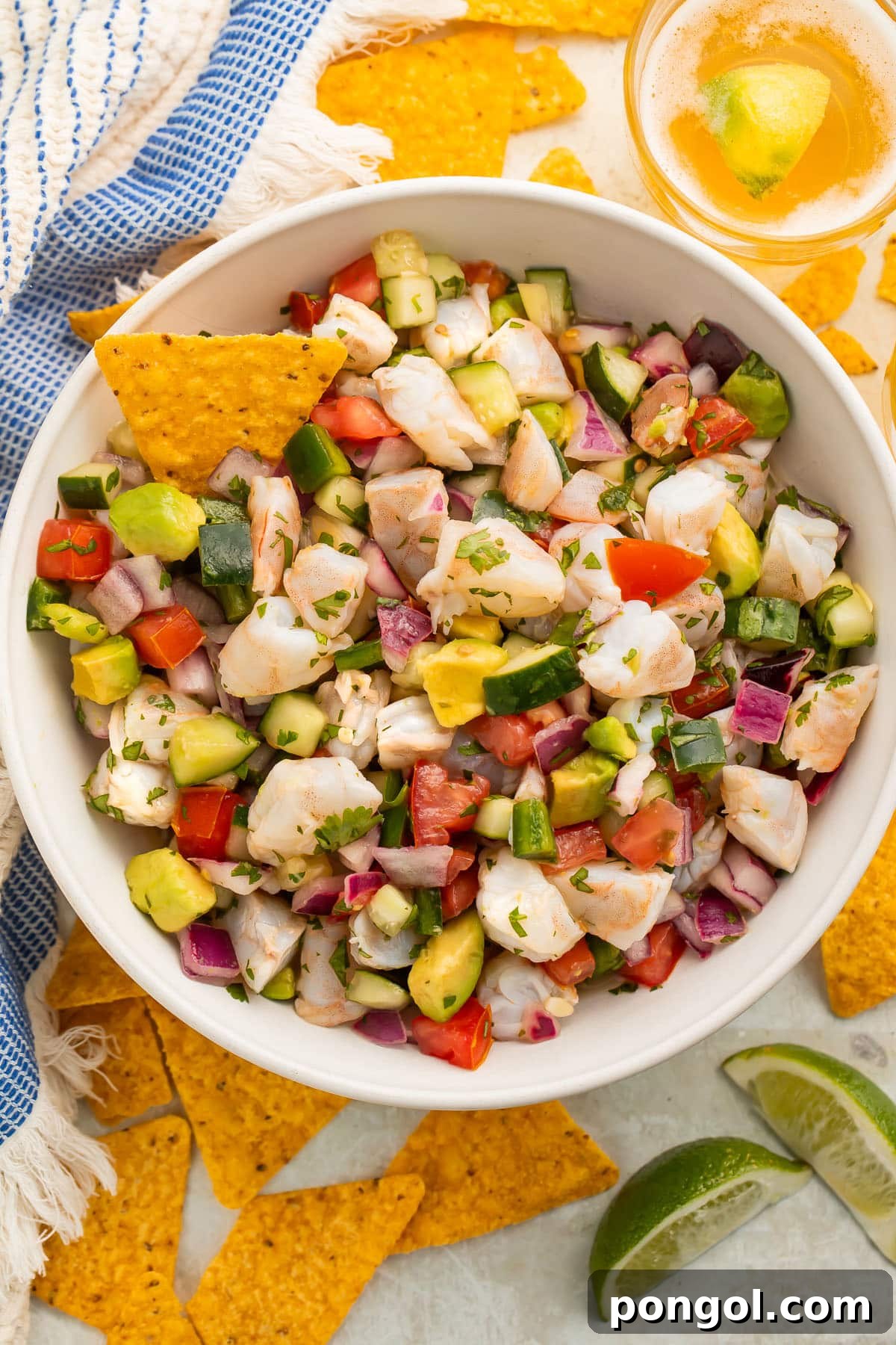 Vibrant Citrus Shrimp Ceviche 3 Overhead view of a bowl of easy shrimp ceviche with chunks of shrimp, red onion, cucumber, avocado, and tomatoes, ready to serve.