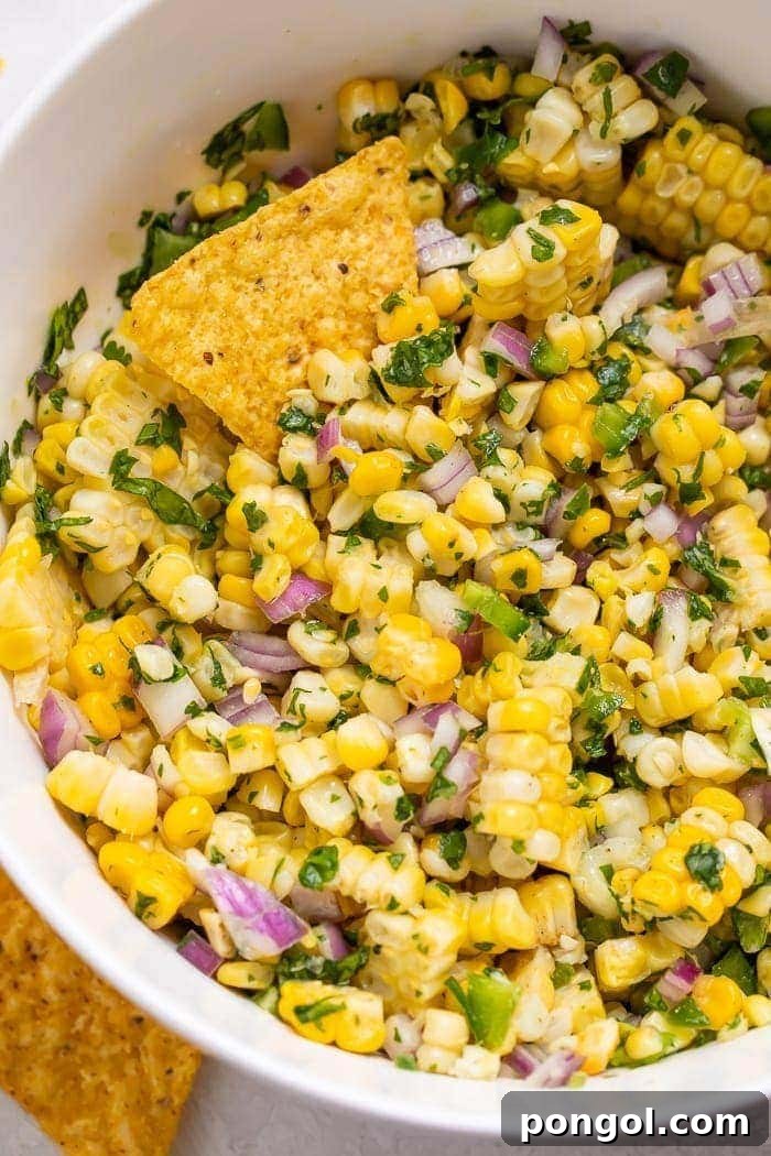 Close-up of corn salsa in a bowl with chips, showcasing vibrant colors and fresh ingredients.