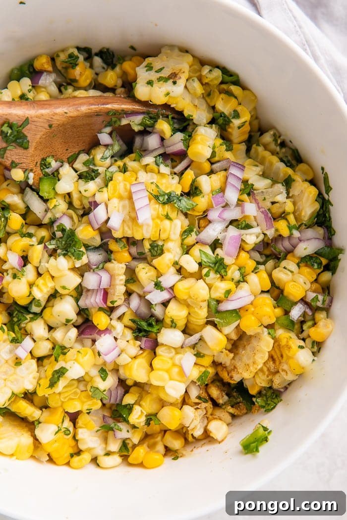 All corn salsa ingredients combined in a mixing bowl before stirring.