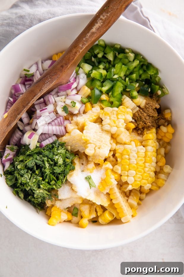 Mixing corn salsa ingredients in a bowl with a spoon.