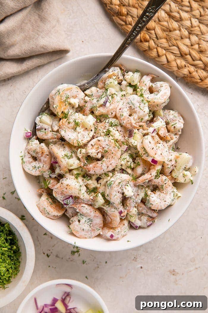 Bowl of creamy shrimp salad, garnished with fresh dill