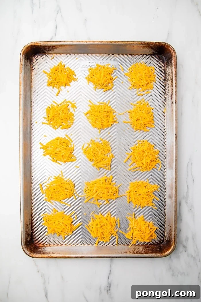 Cheesy Keto Crisps 3 Piles of shredded cheddar cheese on parchment paper before baking
