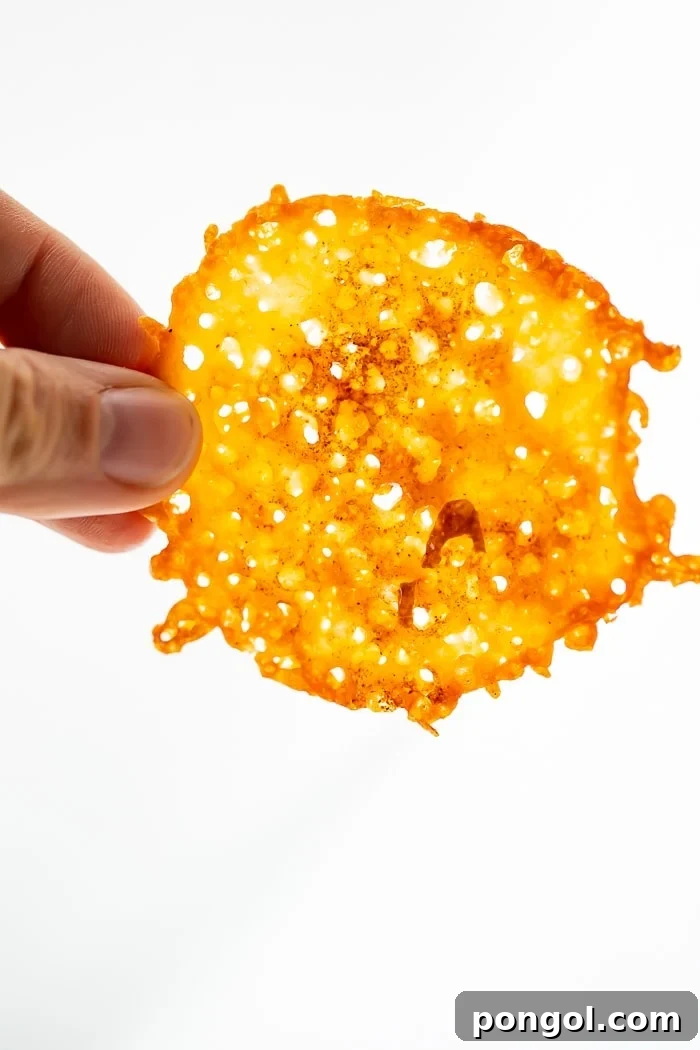 Cheesy Keto Crisps 5 Fingers holding up a perfectly baked keto cheese chip