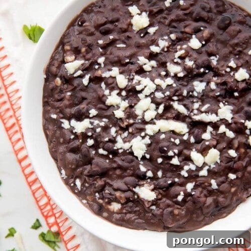 Bowl of refried black beans with queso fresco garnish