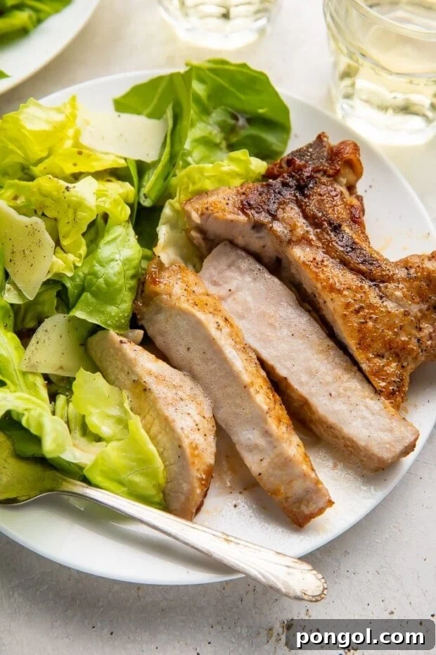 A perfectly cooked and sliced air fryer pork chop, ready to be enjoyed with a side of greens.