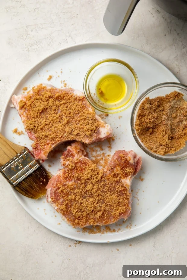 Pork chops being seasoned generously with a sweet and savory spice rub.