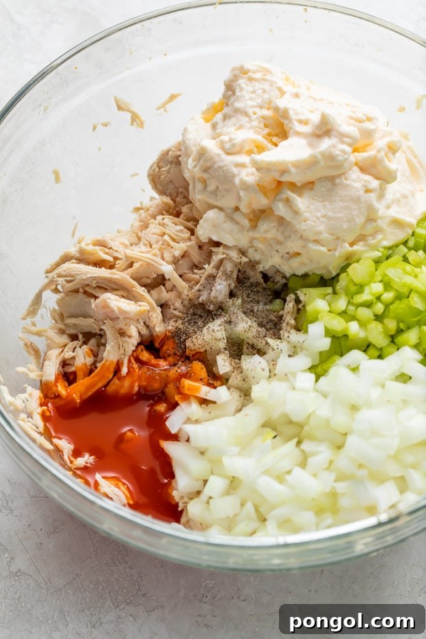 Combining all main ingredients for the Buffalo Chicken Salad in a large mixing bowl.