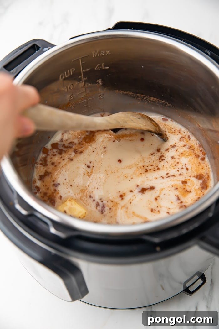 Overhead shot of an Instant Pot inner pot with uncooked rice, creamy almond milk, and various seasonings being stirred before the pressure cooking process begins
