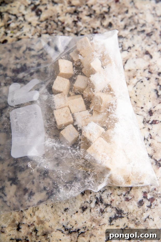 Tofu being tossed in cornstarch