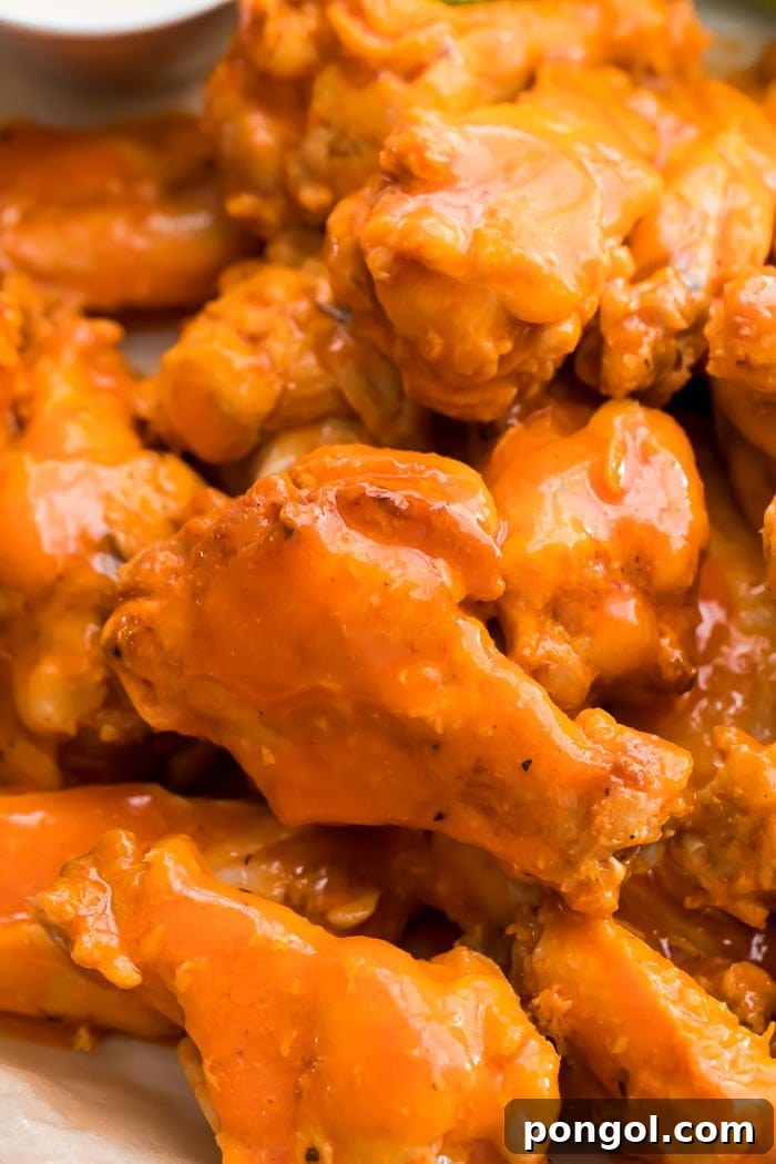 Close-up of a pile of fried chicken wings smothered in buffalo sauce, ready to be eaten.