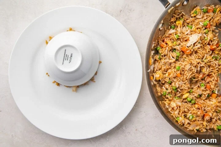 Cooled cooked rice packed firmly into a bowl, inverted onto a large white plate, ready for serving.