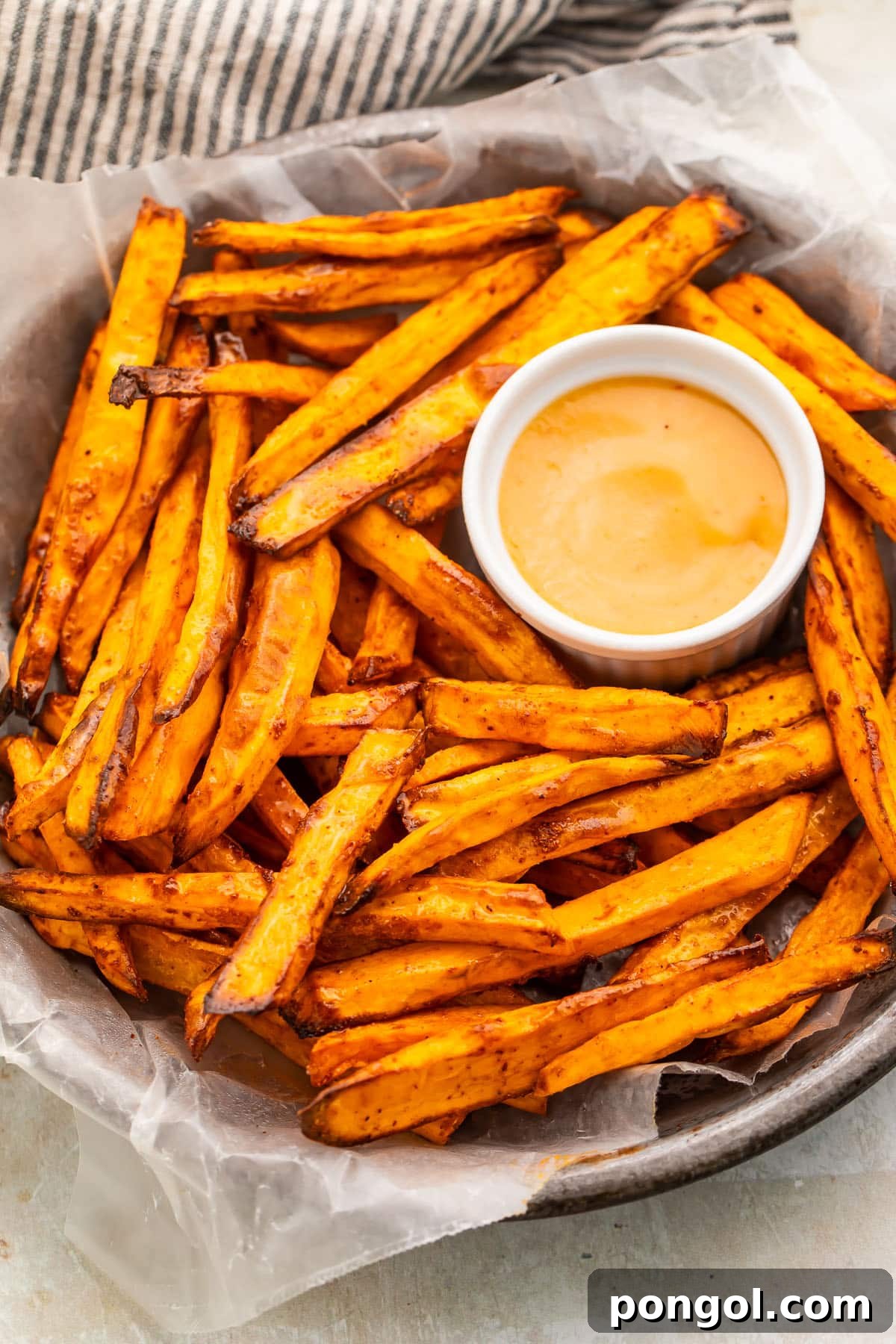 A bowl of homemade air fryer sweet potato fries on a table, perfectly golden and seasoned.