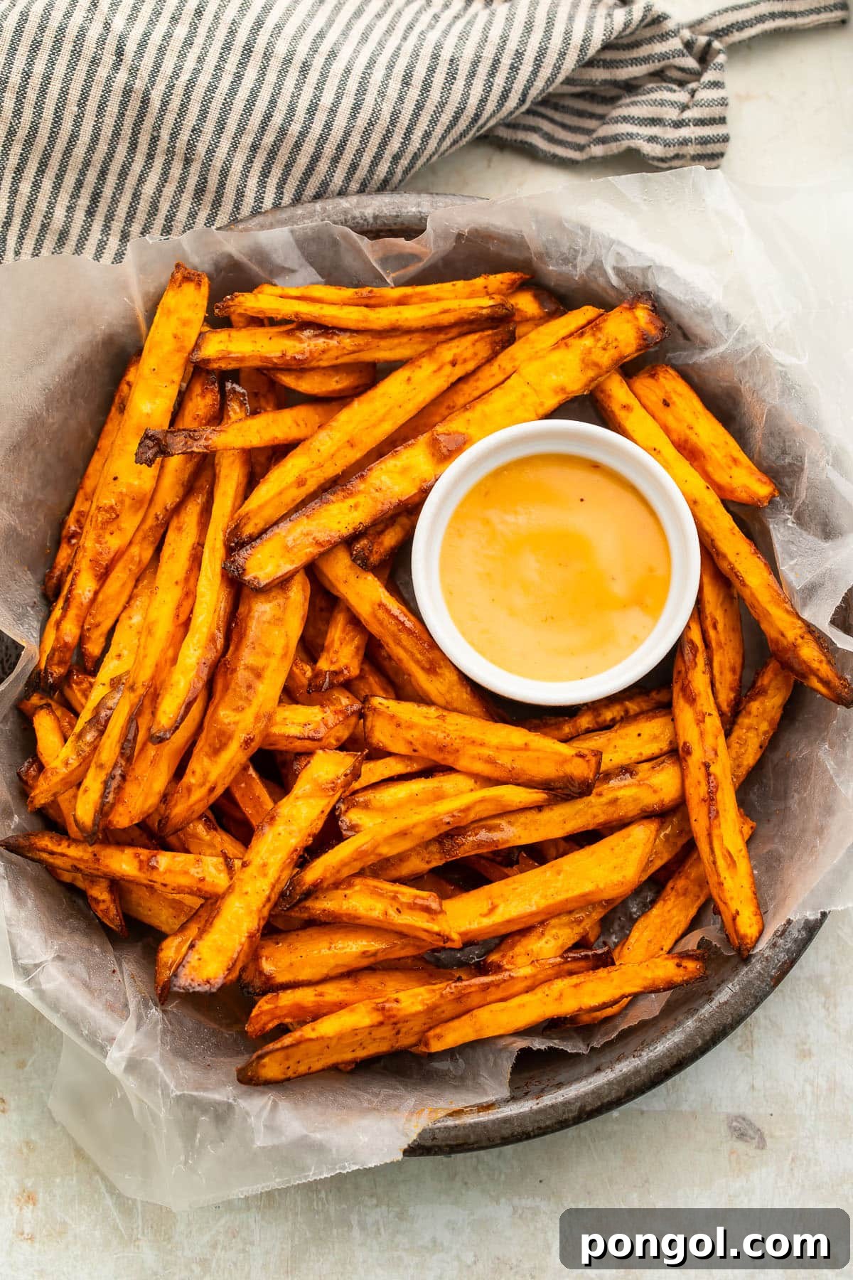 A second shot of a bowl of homemade air fryer sweet potato fries on a table, highlighting their delicious texture.
