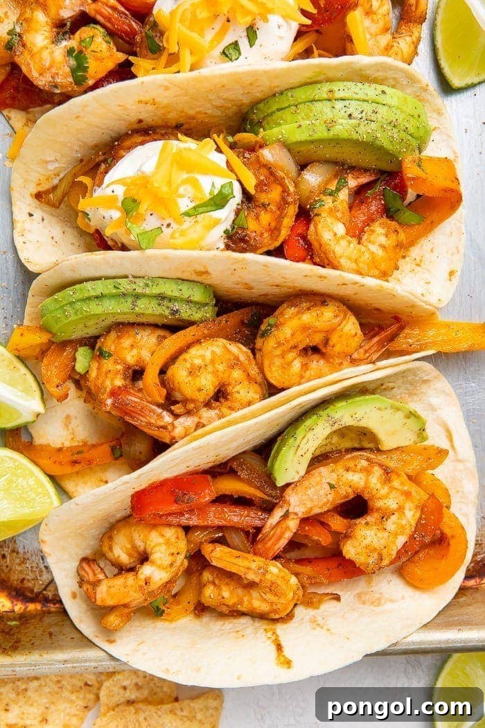 Zesty Lime Shrimp Fajitas 2 Overhead shot of shrimp fajitas inside tortillas topped with avocado slices, sour cream, and cheese