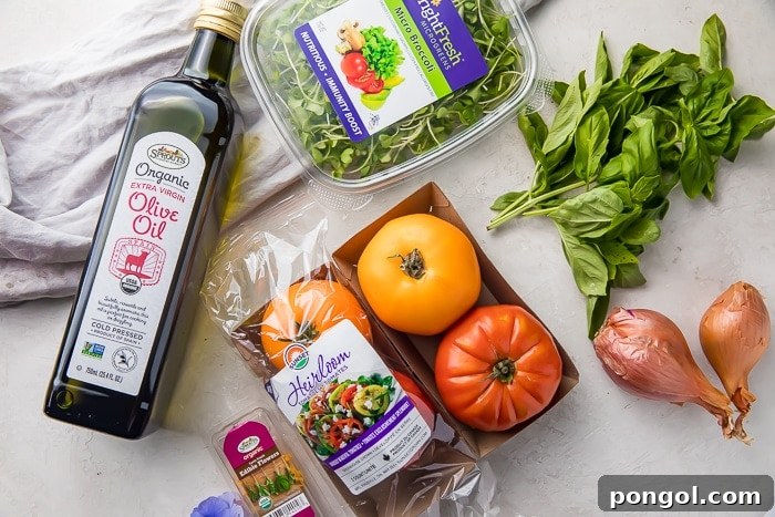 Rainbow Heirloom Tomato Medley 4 An array of fresh ingredients for heirloom tomato salad: a bottle of olive oil, colorful heirloom tomatoes, shallots, basil leaves, and micro broccoli.