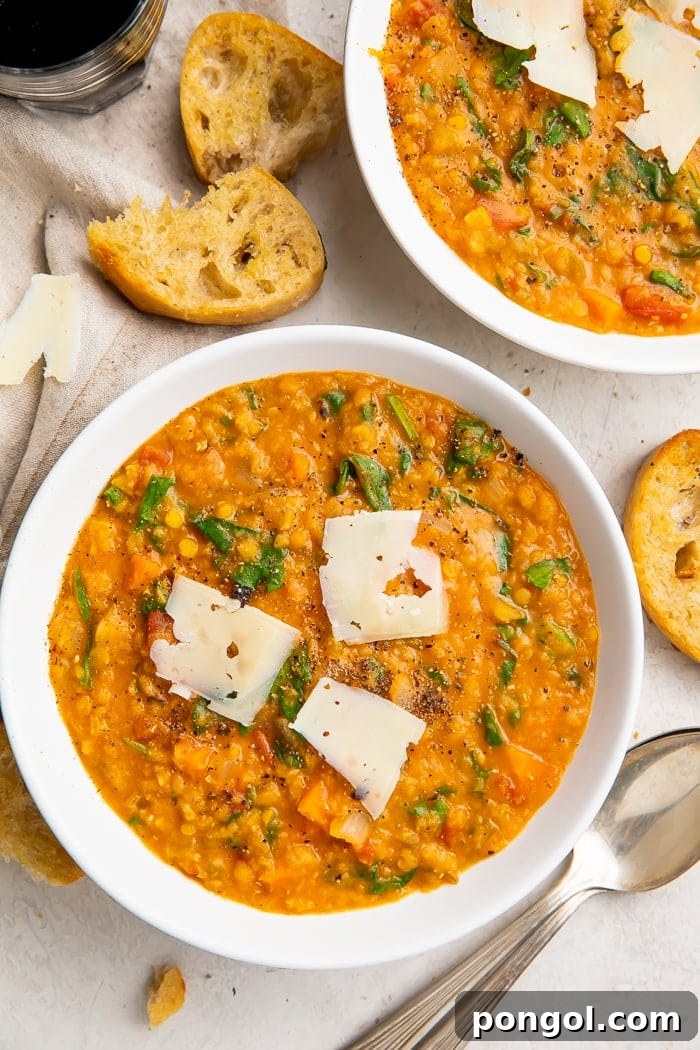 Overhead, zoomed out photo of Instant Pot lentil soup in white bowls, surrounded by crusty bread