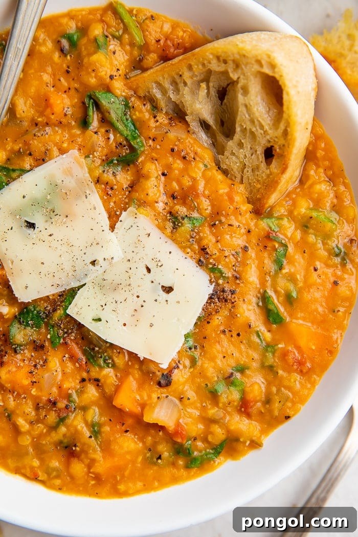 Close up of a bowl of Instant Pot lentil soup, crusty bread, and parmesan cheese