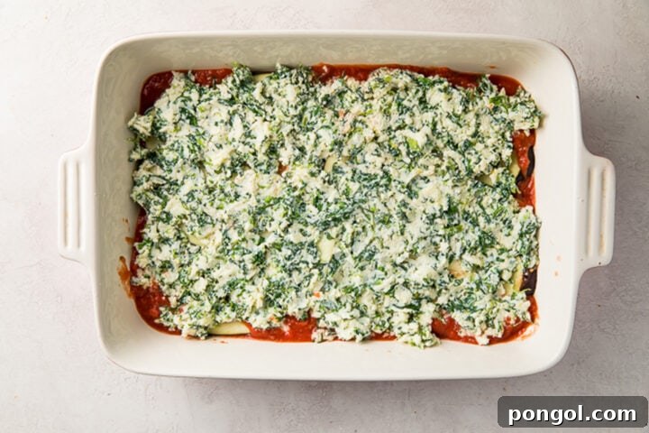 Eggplant slices topped with a creamy spinach ricotta filling in a casserole dish.