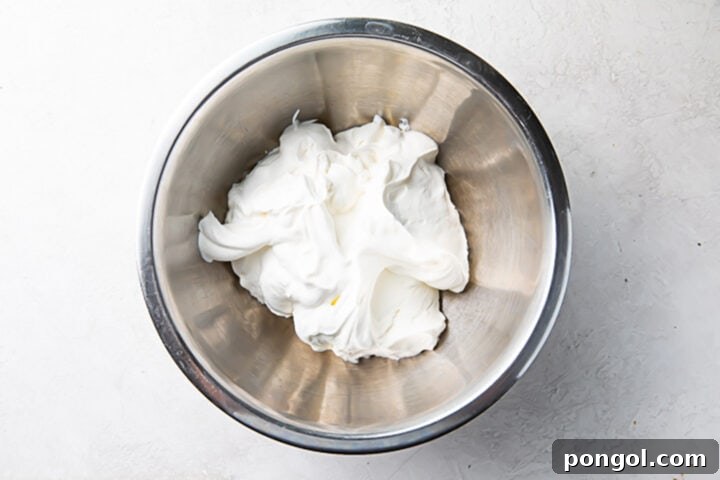 Cream cheese and confectioners' sugar in a large silver mixing bowl, whipped to a smooth consistency.