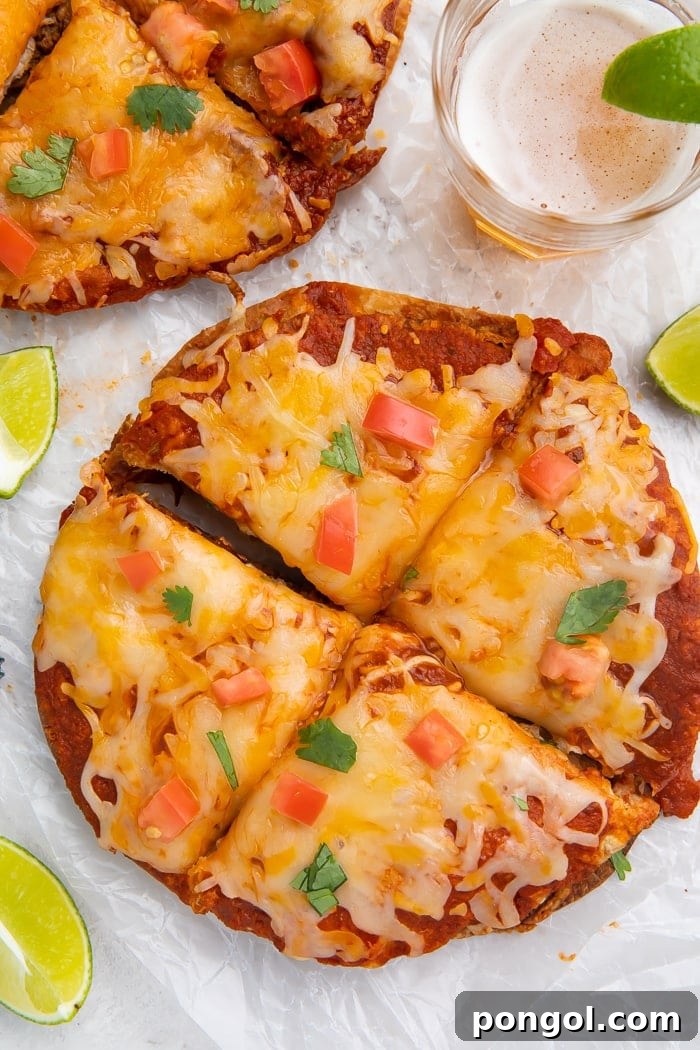 Overhead shot of a freshly made homemade Taco Bell Mexican pizza, topped with vibrant diced tomatoes and fresh cilantro, perfectly cut into four slices. It's accompanied by a refreshing lime wedge, a cool glass of beer, and a retro bottle cap, setting a perfect scene for a casual meal.