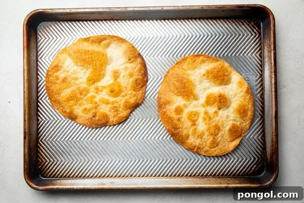 Two baked flour tortillas on top of a baking sheet