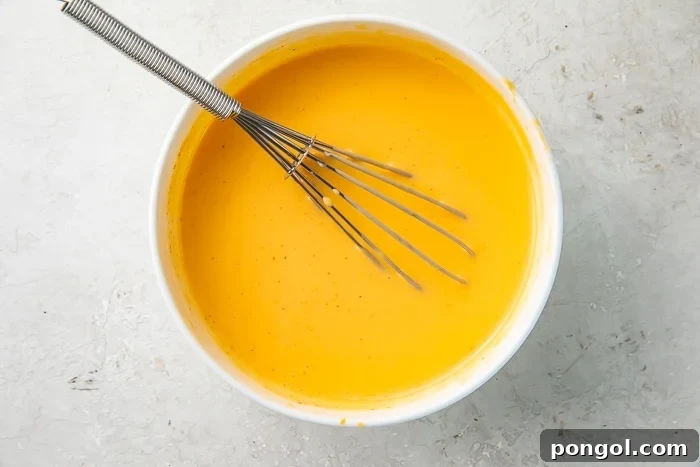 A white bowl filled with Taco Bell nacho cheese sauce and a whisk