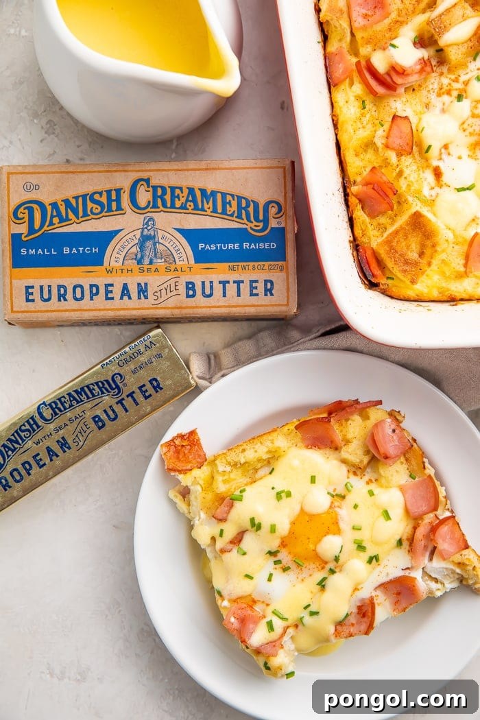 A slice of eggs benedict casserole on a white plate surrounded by a stick of Danish Creamery butter and a kraft box of butter