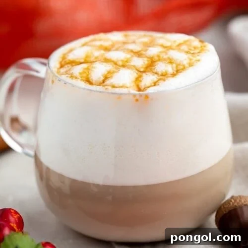 White coffee mug with coffee, whipped cream, and caramel cross-stitch drizzle