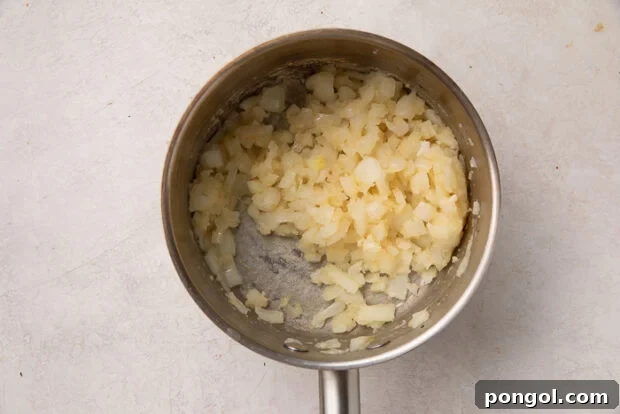 Cheesy Cauliflower Gratin 6 Step 1: Roasting cauliflower on a baking sheet and sautéing onions in a saucepan for the au gratin.
