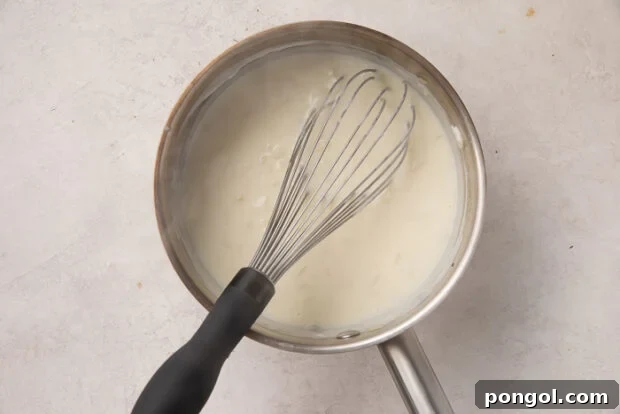 Cheesy Cauliflower Gratin 7 Step 2: Preparing the rich and creamy cheese sauce, stirring in shredded cheese.