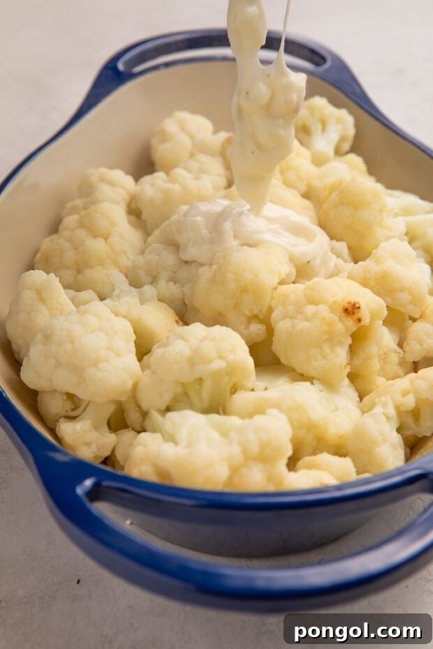 Cheesy Cauliflower Gratin 8 Step 3: Pouring the creamy cheese sauce over roasted cauliflower in a baking dish, ready for baking.