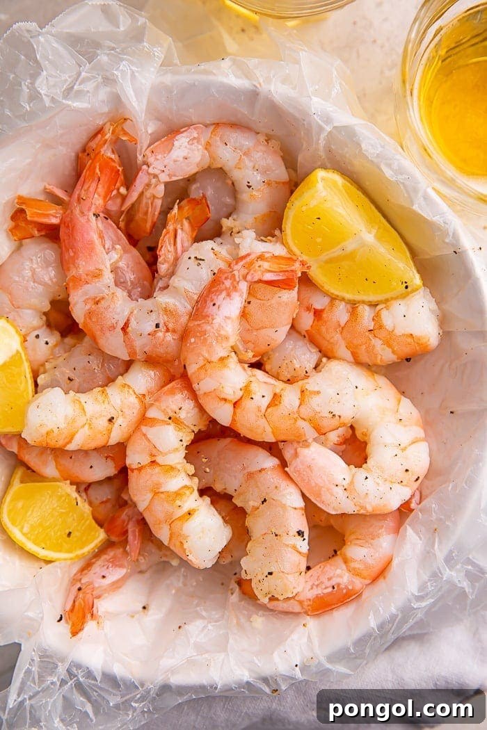 Instant Pot shrimp and lemon wedges inside a bowl lined with parchment paper, showcasing tender, perfectly cooked shrimp.