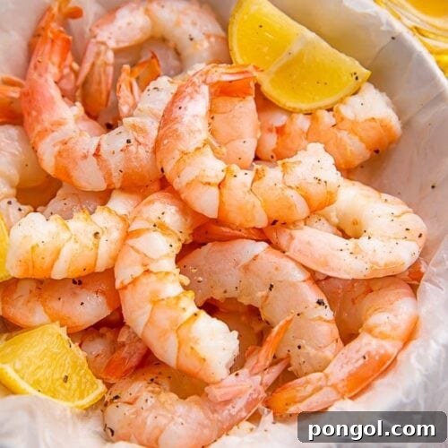 Instant Pot shrimp in a white bowl with lemon wedges