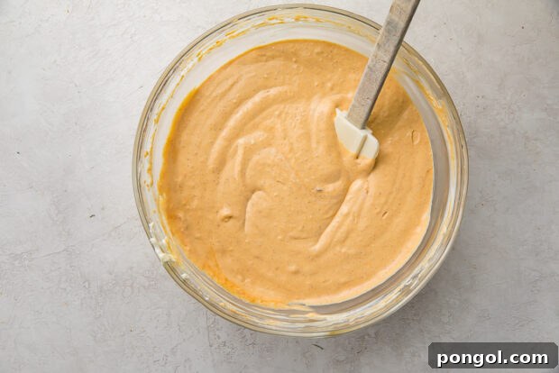 Mixing pumpkin puree and spices into cheesecake batter