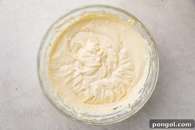 Adding eggs one by one to the cheesecake batter