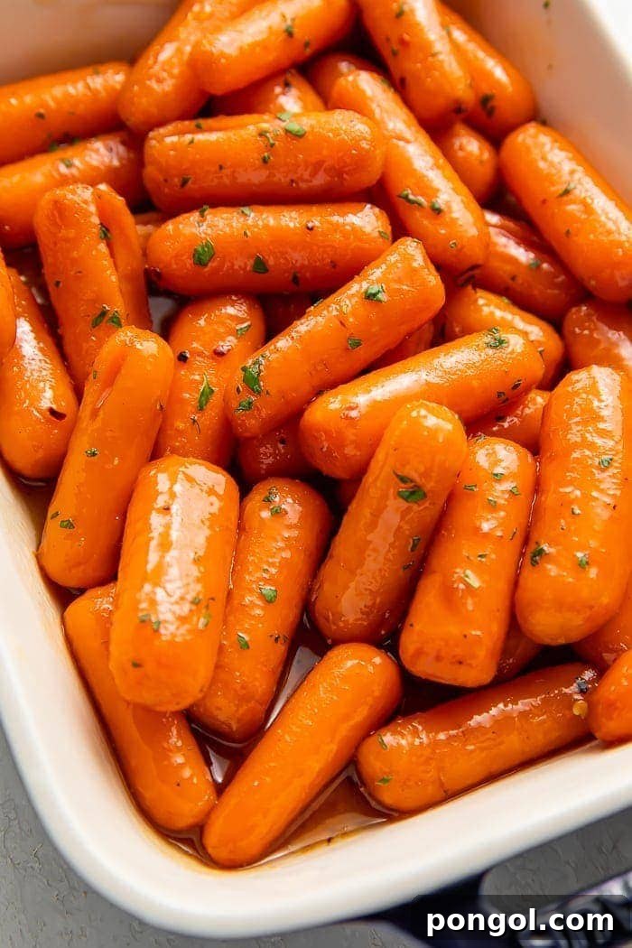 A vibrant dish of freshly made candied carrots, glistening with a sweet, buttery glaze, ready to be served
